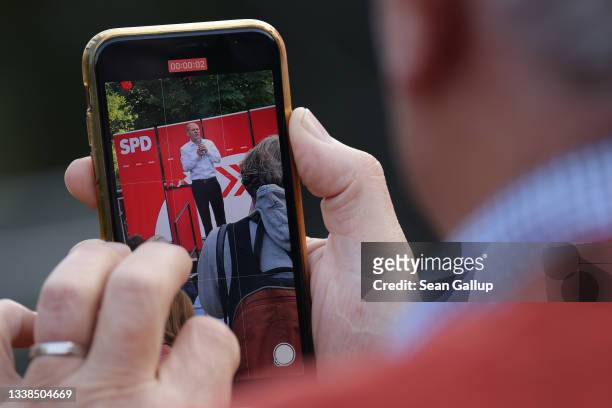 Man with a smartphone records Olaf Scholz, chancellor candidate of the German Social Democrats , speaking at an election campaign rally on September...
