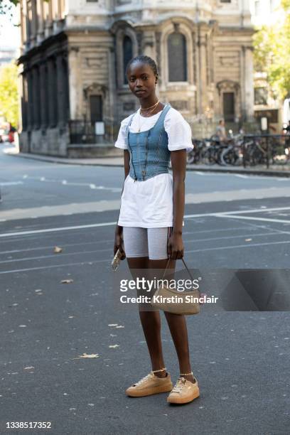 Model wears Fenty trainers, grey cycling shorts, white t shirt, a gold bag and a denim corset top during London Fashion Week September 2019 on...