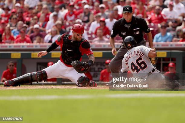 Jeimer Candelario of the Detroit Tigers slides into home plate to score a run past Tucker Barnhart of the Cincinnati Reds in the sixth inning at...