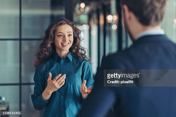 businesswoman talking to a colleague - discussion imagens e fotografias de stock