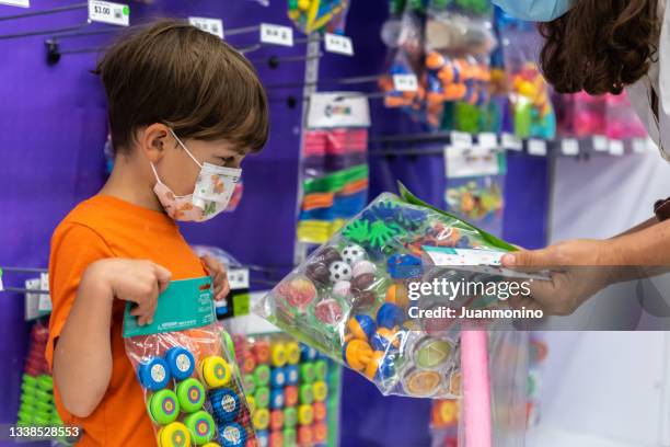 little boy shopping for toys for his piñata birthday party - loja de brinquedos imagens e fotografias de stock