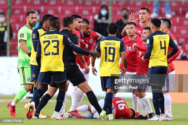 Junior Sornoza of Ecuador argues wih Charles Aránguiz and Jean Meneses of Chile as Claudio Baeza of Chile lies on the pitch during a match between...