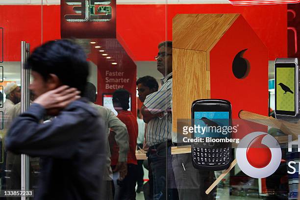 Customers stand inside a Vodafone India Ltd. Retail store in Mumbai, India, on Tuesday, Nov. 15, 2011. Indian investigators raided the offices of...