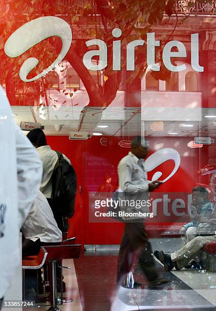 The Bharti Airtel Ltd. Logo is seen through a window at a retail store in Mumbai, India, on Tuesday, Nov. 15, 2011. Indian investigators raided the...