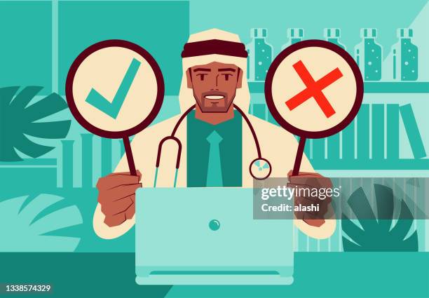 handsome young doctor using a laptop providing telemedicine services holding an ok sign and no sign - arabic doctor stock illustrations