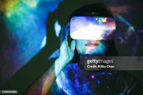 asian woman wearing virtual reality headset with outer space image projected on her - sensory perception stock photos et images de collection