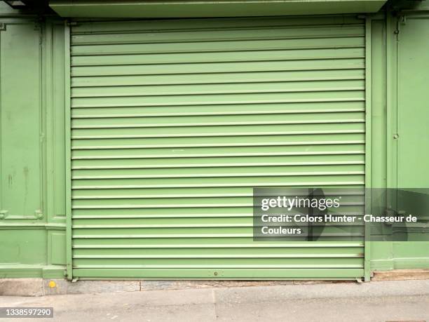 green facade of a closed parisian restaurant and sidewalk - roller shutter stock pictures, royalty-free photos & images