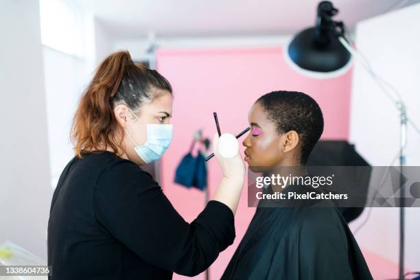 make up artist wearing protective mask working in studio with model - covid bts stock pictures, royalty-free photos & images