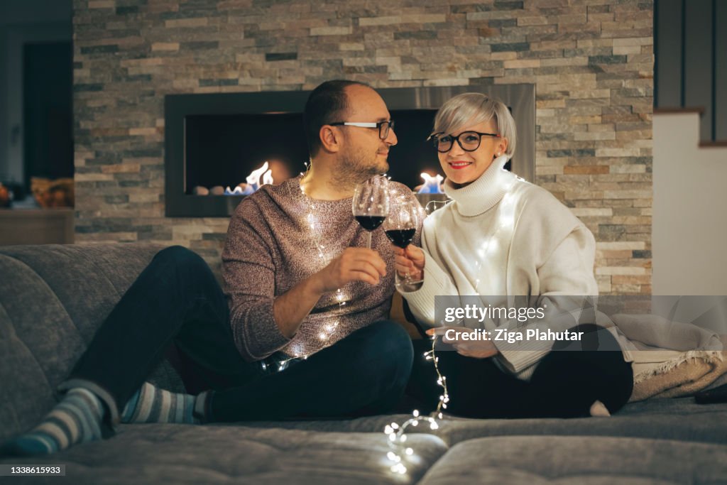 Married couple celebrating new years eve in the comfort of home with a glass of wine