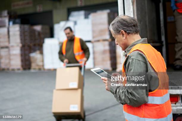 senior male transportation foreman using digital tablet - logistica imagens e fotografias de stock
