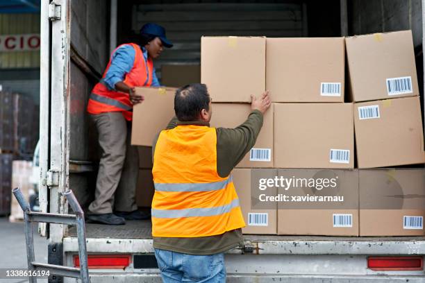 trucker and loading dock worker arranging boxes in vehicle - loading boxes stock pictures, royalty-free photos & images