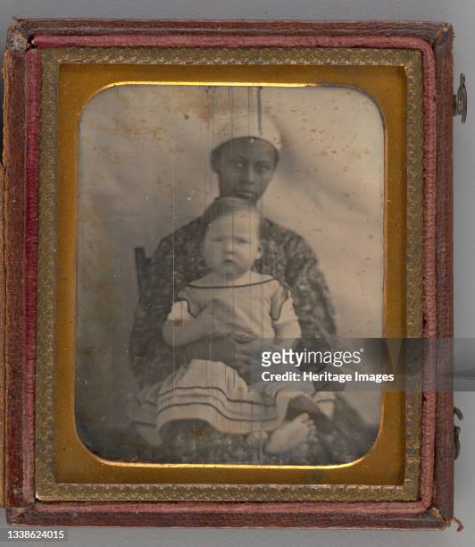 Untitled , 1850. Black-and-white portrait photograph in a gold mat and frame of a white toddler in a dress with a striped skirt seated in the lap of...
