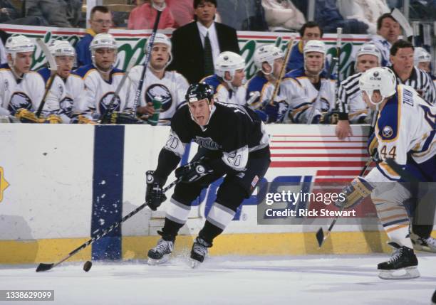 The Buffalo Sabres players watch from the team bench as Ray Ferraro of Canada and Center for the Los Angeles Kings skates in motion on the ice during...