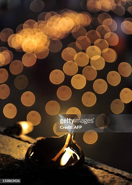 An oil wick lamp sits on a wall at a temple for the Hindu God Shiva during the Karthigai Deepam, a festival where devotees light oil wick lamps at...