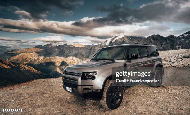 land rover defender against the alps at passo dello stelvio close to bormio - land rover stock pictures, royalty-free photos & images