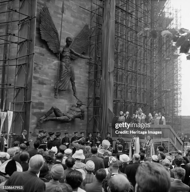 Crowd of people watching the unveiling ceremony of the statue St Michael and the Devil by sculptor Jacob Epstein at Coventry Cathedral. The statue of...
