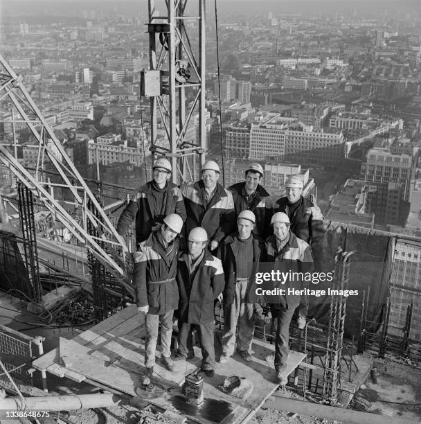 The team of Laing workers who worked on dismantling a tower crane posed for a photo on the roof of a tower, possibly Cromwell Tower, on the Barbican...