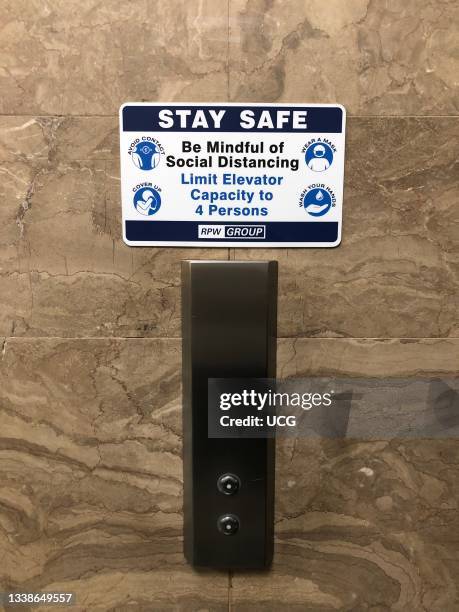 Stay Safe, Social Distancing and limited capacity sign near elevators in Art Deco Office Building, Manhattan, New York.