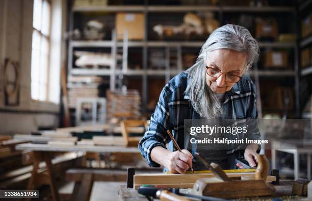 senior female carpenter working on her product. small business concept. - retraités qui travaillent photos et images de collection