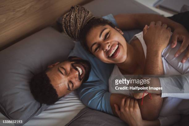 portrait of young couple playing on bed indoors at home, laughing. - legame affettivo foto e immagini stock