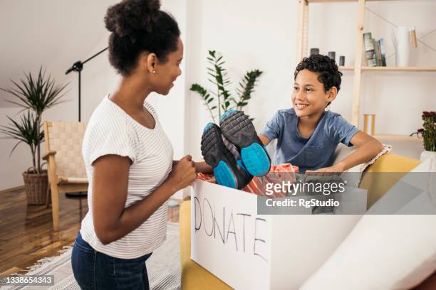 mother and son preparing a box of clothes for donation - donation box stock pictures, royalty-free photos & images