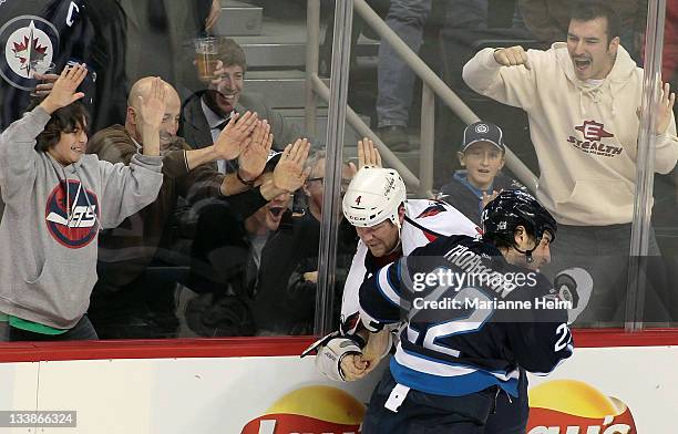 Chris Thorburn of the Winnipeg Jets and John Erskine of the Washington Capitals fight while fans react in NHL action at the MTS Centre on November...