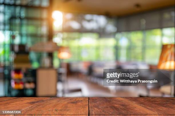 wood table top and blurred bokeh office interior space background - bürotisch stock-fotos und bilder
