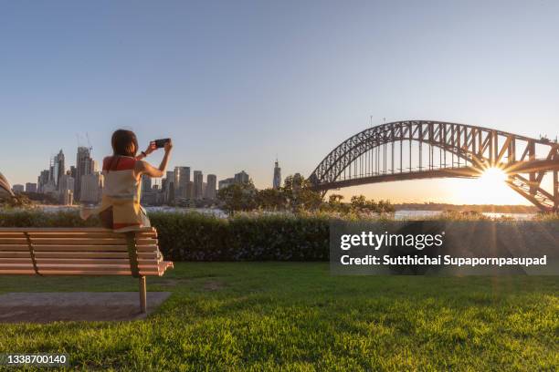 female tourtist taking a photo sydney harbour bridge with her smartphone. - australia tourism stock pictures, royalty-free photos & images