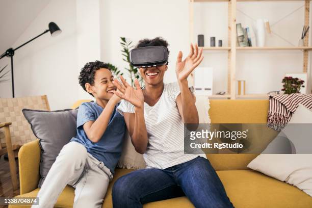 mutter und sohn mit einem virtual-reality-headset und spaß haben - vr goggles woman stock-fotos und bilder