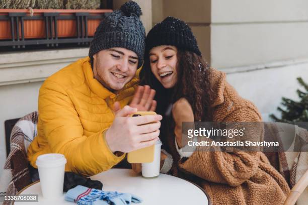 young woman and man celebrating christmas with family by video call in cafe terrace - 18 23 months stock pictures, royalty-free photos & images