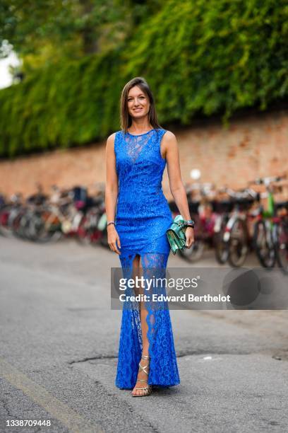 Guest wears a royal blue lace sleeveless / V-neck / short tube dress with a mermaid train, a green and gold shiny leather snake print pattern clutch,...