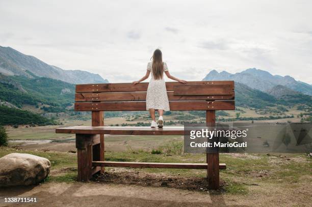 young woman on a giant bench in a mountain area - 特大 個照片及圖片檔