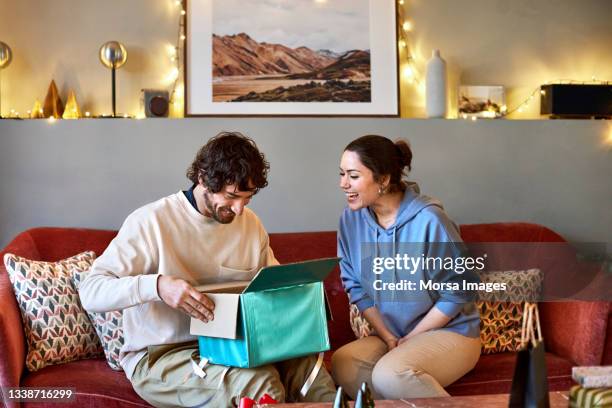 happy couple with christmas present at home - open gift stock pictures, royalty-free photos & images