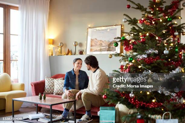 couple talking on sofa at home during christmas - natal casal imagens e fotografias de stock