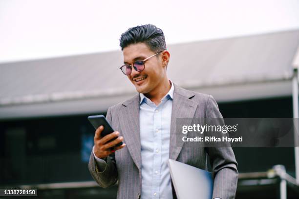 senior executive man talking on the phone while walking at corporate offices - asian businessman phone stockfoto's en -beelden