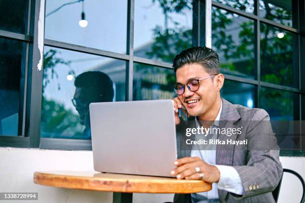 senior executive man talking on the phone and using laptop for business discussion - malay archipelago stock pictures, royalty-free photos & images