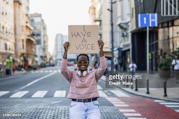 giovane donna che protesta per strada contro il razzismo - giustizia sociale foto e immagini stock