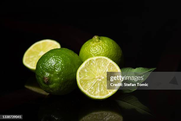 fresh green lime fruits on dark background - lime overhead stock pictures, royalty-free photos & images