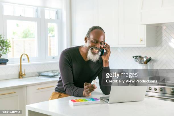 senior black man speaking on the phone with his doctor about prescription medication - pharma people stockfoto's en -beelden