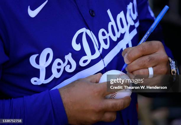 Manager Dave Roberts of the Los Angeles Dodgers wearing their city connect uniform signs autographs for fans prior to the start of the game against...