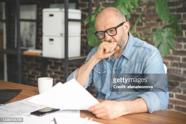 mature adult man working from office ( with laptop, paperwork, negative emotion) - filing documents stock pictures, royalty-free photos & images