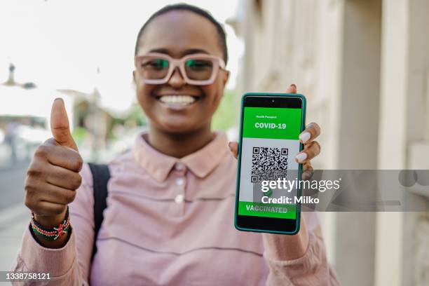 african-american woman shows certificate of vaccination on mobile phone - showing identification stock pictures, royalty-free photos & images