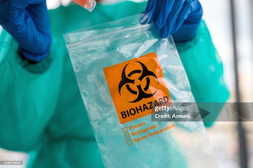 Médica do sexo feminino colocando amostra de teste COVID-19 em saco de risco biológico