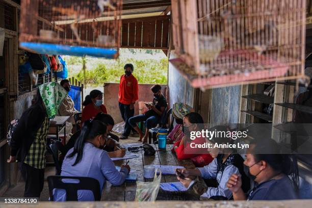 Villagers of Kampung Gana fill in their CanSino vaccination consent form during a COVID-19 vaccination outreach program on September 06, 2021 in Kota...