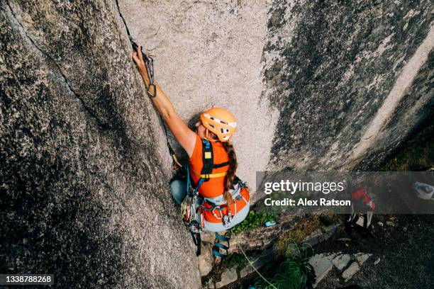 a women reaches up really high to place a piece of equipment while aid rock climbing - great effort stock pictures, royalty-free photos & images