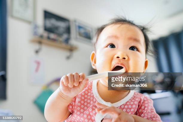 asian mother try to feeding and motivate first meal for her daughter (2-6 month)  at home - asian spoon feeding stock pictures, royalty-free photos & images