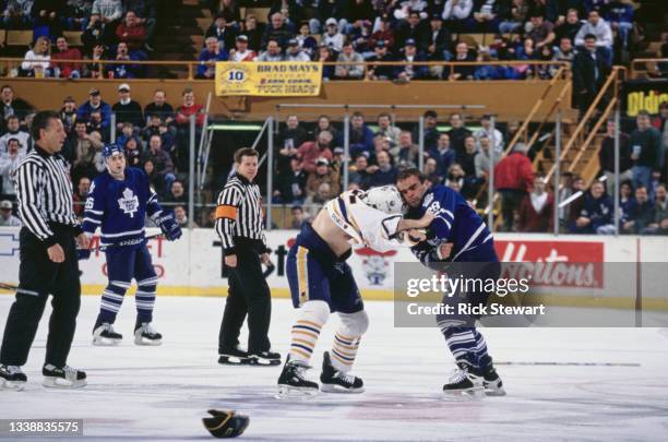 The referees look on as Tie Domi of Canada and Right Wing the Toronto Maple Leafs and compatriot Rob Ray of the Buffalo Sabres engage in a fight...
