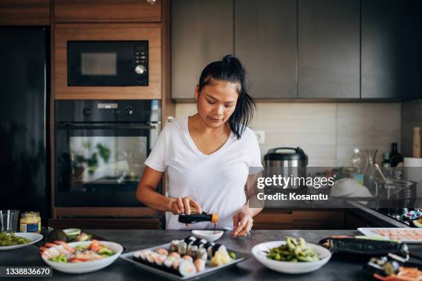 sushi chef, thai ethnicity pouring the soya sauce into bowl, making the last preparation for sushi meal - shrimp edamame stock pictures, royalty-free photos & images