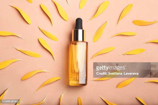 a cosmetic bottle and yellow gerbera on the beige background. - cosmetic bottle stockfoto's en -beelden