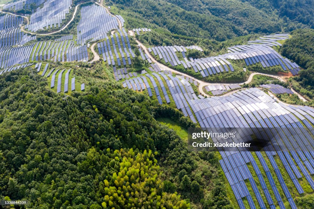 A bird's eye view of the solar power plant and lush woods on the top of the mountain